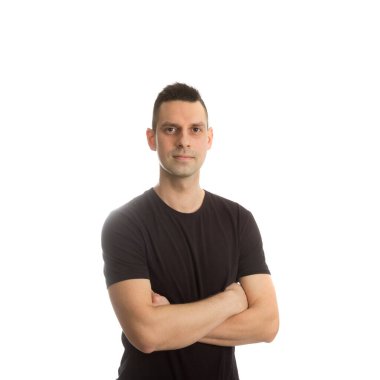 Sıradan bir genç adam kollarını kavuşturmuş kameraya bakıyor.