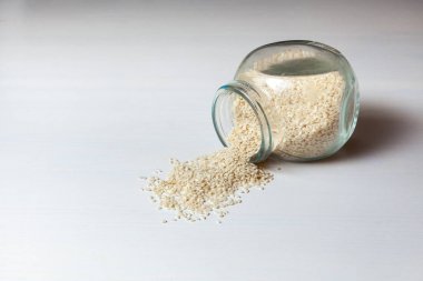 Susam beyaz masa arka plan üzerinde cam kavanoza Close-up