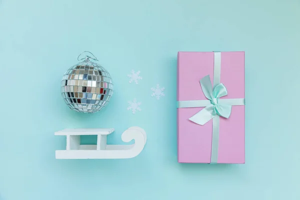 Просто минимальная композиция зимних объектов украшения бальные сани подарочные коробки изолированы на синем пастельном модном фоне — стоковое фото