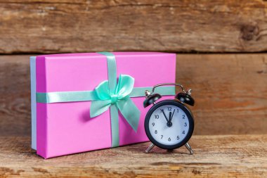 Ahşap zemin üzerinde çalar saat ve hediye kutusu