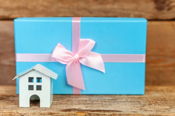Miniatur-weißes Spielzeughaus und Geschenkschachtel auf Holzgrund — Stockfoto