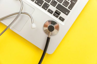 Stetoskop klavye dizüstü bilgisayar sarı arka plan üzerinde izole. Modern tıbbi Bilgi teknolojisi ve sofware gelişmeler kavramı. Bilgisayar ve gadget tanılama ve onarım