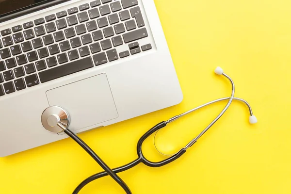 Stethoscope keyboard laptop computer isolated on yellow background. Modern medical Information technology and sofware advances concept. Computer and gadget diagnostics and repair