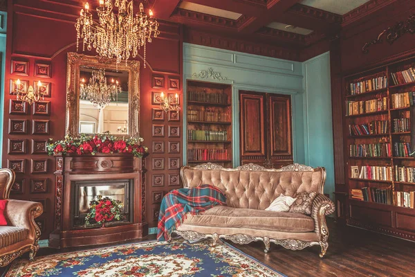 Ev kütüphanesinin lüks klasik iç. Kitaplık, kitap, kol koltuğu, kanepe ve şömineile oturma odası