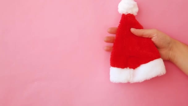 Simply minimal design female woman hand press squeezing Christmas Santa hat isolated on pink pastel colorful trendy background — Stock Video