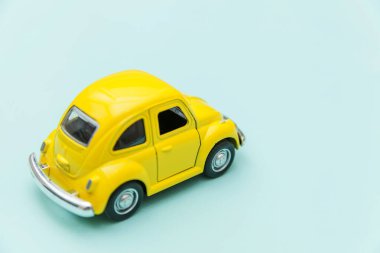 Sarı antika oyuncak araba mavi pastel renkli arka planda izole edilmiş.