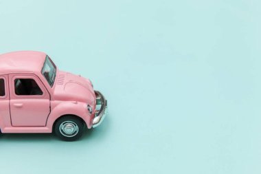 Pembe eski model oyuncak araba mavi pastel renkli arka planda izole edilmiş.