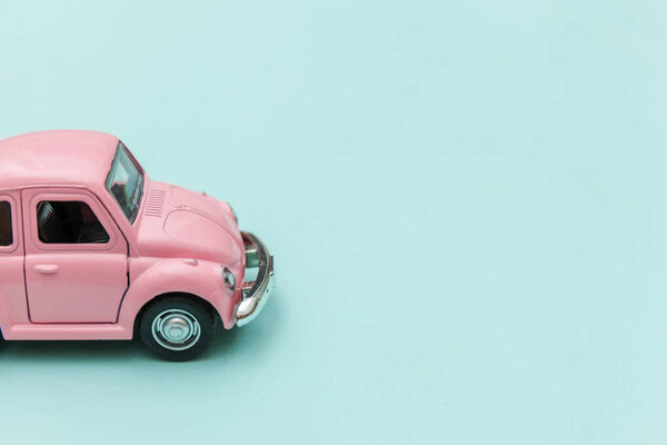 Розовый винтажный ретро игрушечный автомобиль изолирован на голубом пастельном красочном фоне
