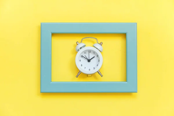 Ringing twin bell vintage alarm clock in blue frame isolated on yellow colorful trendy background — Stock Photo, Image