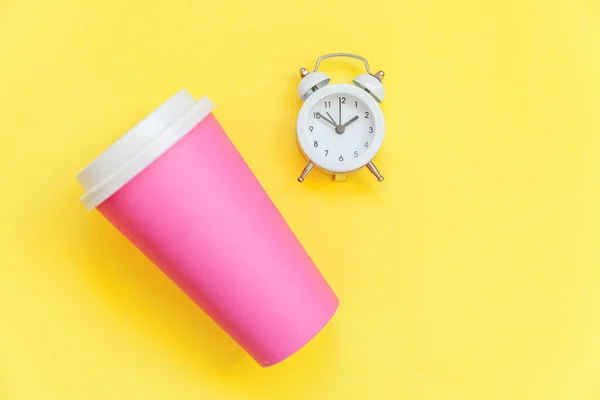 Jednoduše plochý návrh na růžovou papírovou kávu šálek a budík izolovaný na žlutém barevném módním pozadí — Stock fotografie