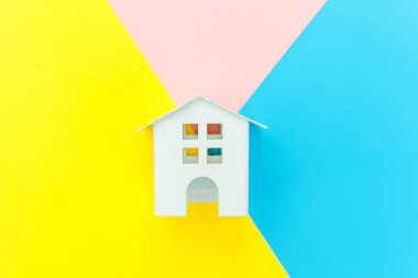 Mavi sarı pembe pastel renkli trendy geometrik arka planda izole minyatür beyaz oyuncak ev