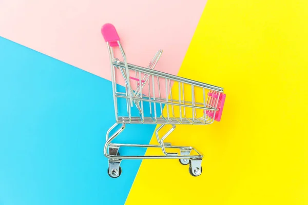 小型超市杂货玩具推车隔离在蓝色黄色和粉红色柔和的彩色背景 — 图库照片