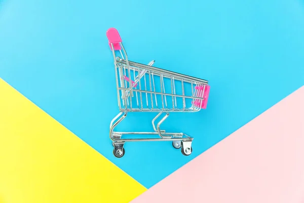 Pequeño supermercado supermercado juguete empuje carro aislado en azul amarillo y rosa pastel colorido fondo — Foto de Stock