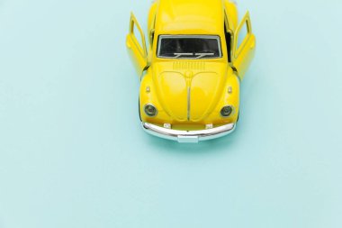 Sarı antika oyuncak araba mavi pastel renkli arka planda izole edilmiş.