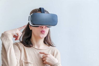 Beyaz arka planda sanal gerçeklik gözlüğü başlığı takan genç kadın gülümse. Sanal gerçeklik gözlüğü takan akıllı telefon. Teknoloji, simülasyon, yüksek teknoloji, video oyunu konsepti.