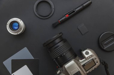 DSR kamera sistemi olan fotoğrafçı işyeri, kamera temizleme seti, siyah masa arka planında lens ve kamera aksesuarı. Hobi seyahat fotoğraf konsepti Düz görünüm kopya alanı yatıyordu