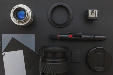 DSR kamera sistemi olan fotoğrafçı işyeri, kamera temizleme seti, siyah masa arka planında lens ve kamera aksesuarı. Hobi seyahat fotoğraf konsepti Düz görünüm kopya alanı yatıyordu