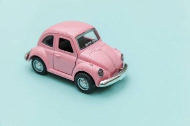 Pembe eski model oyuncak araba mavi pastel renkli arka planda izole edilmiş.