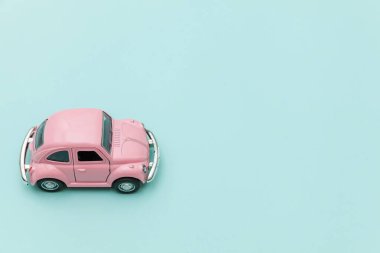 Pembe eski model oyuncak araba mavi pastel renkli arka planda izole edilmiş.