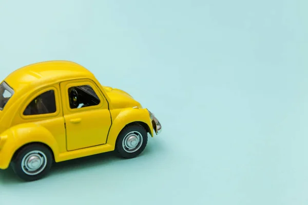 Gelbes Retro-Spielzeugauto isoliert auf blauem pastellfarbenem Hintergrund — Stockfoto