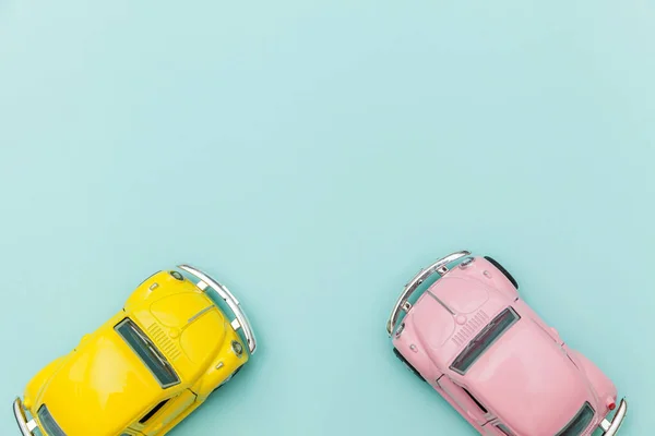 青いパステルカラフルな背景に隔離された2つの黄色のピンクのヴィンテージレトロなおもちゃの車 — ストック写真