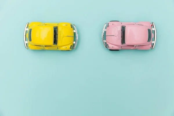 Două galben roz vintage retro jucărie mașină izolat pe fundal albastru pastel colorat — Fotografie, imagine de stoc
