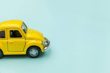 Sarı antika oyuncak araba mavi pastel renkli arka planda izole edilmiş.