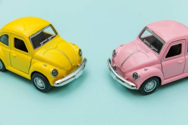 Mavi pastel renkli arka planda izole edilmiş iki sarı, eski model oyuncak araba.