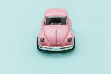 Pembe eski model oyuncak araba mavi pastel renkli arka planda izole edilmiş.