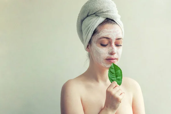Visage de femme avec feuille verte et crème ou masque nourrissant — Photo