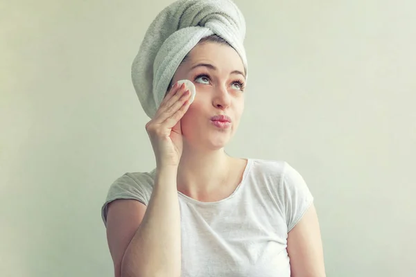 Χαμογελαστή γυναίκα με πετσέτα στο κεφάλι με απαλό υγιές δέρμα αφαίρεση κάνει με βαμβακερό pad απομονωθεί σε λευκό φόντο — Φωτογραφία Αρχείου