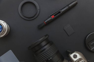 DSR kamera sistemi olan fotoğrafçı işyeri, kamera temizleme seti, siyah masa arka planında lens ve kamera aksesuarı. Hobi seyahat fotoğraf konsepti Düz görünüm kopya alanı yatıyordu