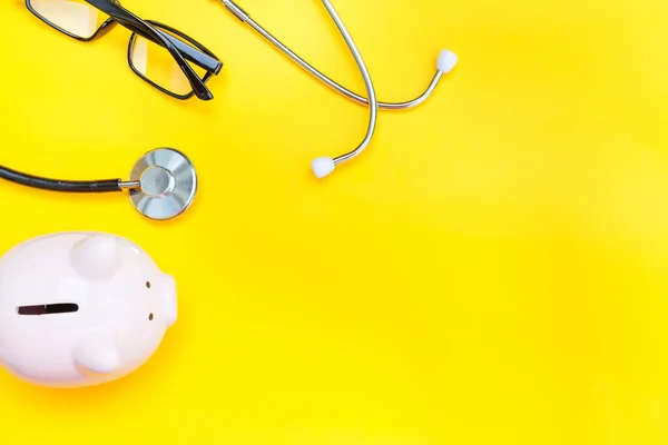 Equipamento médico medicina estetoscópio ou fonendoscópio óculos de banco piggy isolado no fundo amarelo na moda — Fotografia de Stock