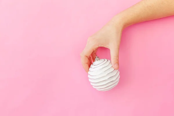 Simplesmente design mínimo mulher feminina mão segurando bola ornamento de Natal isolado no pastel rosa colorido fundo da moda — Fotografia de Stock