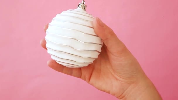 Gewoon minimale ontwerp vrouwelijke vrouw hand houden kerst ornament Fir Tree geïsoleerd op roze pastel kleurrijke trendy achtergrond — Stockvideo