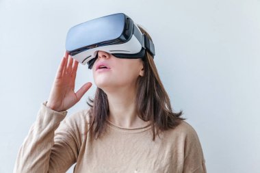 Beyaz arka planda sanal gerçeklik gözlüğü başlığı takan genç kadın gülümse. Sanal gerçeklik gözlüğü takan akıllı telefon. Teknoloji, simülasyon, yüksek teknoloji, video oyunu konsepti