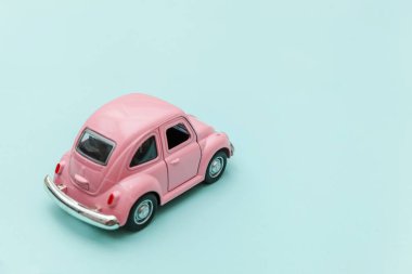 Pembe eski model oyuncak araba mavi pastel renkli arka planda izole edilmiş.