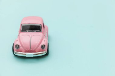 Pembe eski model oyuncak araba mavi pastel renkli arka planda izole edilmiş.