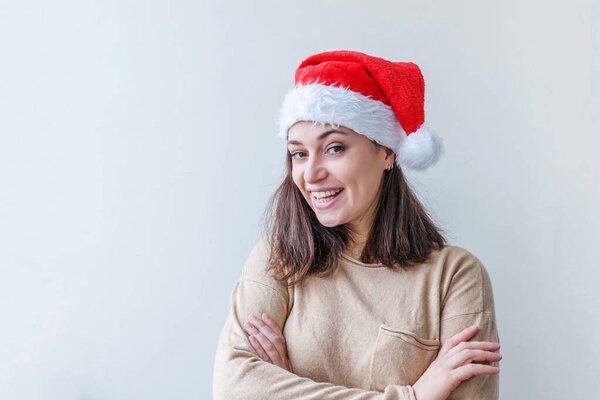 Beautiful girl in red Santa Claus hat isolated on white background looking happy and excited. Young woman portrait, true emotions. Happy Christmas and New Year holidays