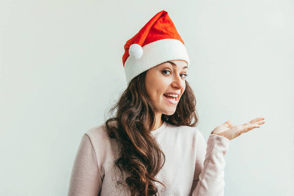 Beautiful girl in red Santa Claus hat showing open palm hand solated on white background