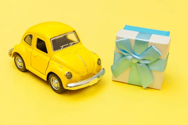 単に流行の黄色の背景に孤立屋根の上にギフトボックスを提供黄色のヴィンテージレトロなおもちゃの車を設計します。クリスマスの誕生日バレンタインデーのお祝いプレゼントロマンチックなコンセプト — ストック写真
