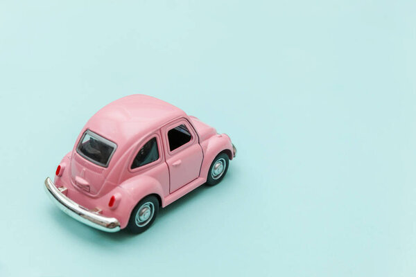 Розовый винтажный ретро игрушечный автомобиль изолирован на голубом пастельном красочном фоне
