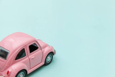 Pembe eski model oyuncak araba mavi pastel renkli arka planda izole edilmiş.