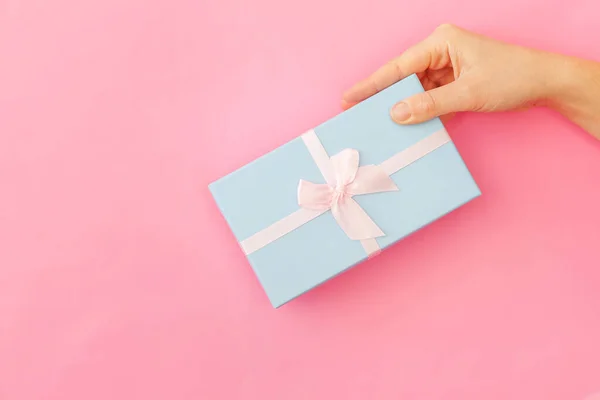 Po prostu projektowana kobieta dłoń niebieski prezent pudełko na białym tle na różowym pastelowych kolorowy tło — Zdjęcie stockowe