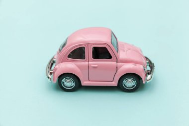 Mavi pastel renkli arka planda izole edilmiş pembe eski model oyuncak arabaya sahip basit bir tasarım. Otomobil ve ulaşım sembolü. Şehir trafiği konsepti. Metin için alanı kopyala