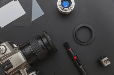 DSR kamera sistemi olan fotoğrafçı işyeri, kamera temizleme seti, siyah masa arka planında lens ve kamera aksesuarı. Hobi seyahat fotoğrafçılık konsepti. Düz görünüm kopyalama alanı