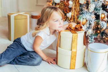 Noel arifesinde Noel ağacının yanında hediye kutusu olan küçük bir kız. Kış dekorasyonuyla aydınlık odada genç bir çocuk. Evde mutlu bir aile. Noel Yeni Yıl Kutlama Konsepti Zamanı