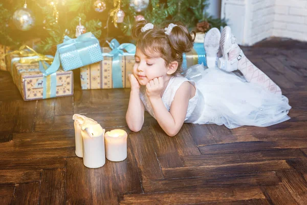 Klein meisje met geschenkdoos in de buurt van kerstboom thuis — Stockfoto