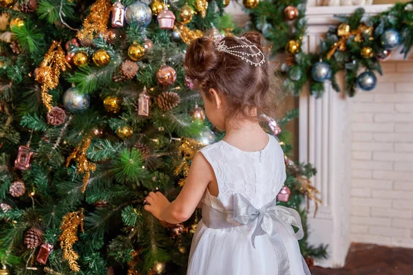 Новый год 2020 С Рождеством Христовым! Маленькая девочка украшает елку в декабре канун Рождества дома. Молодой парень в спальне с зимним декором. Время праздновать концепцию — стоковое фото