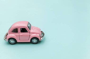 Pembe eski model oyuncak araba mavi pastel renkli arka planda izole edilmiş.